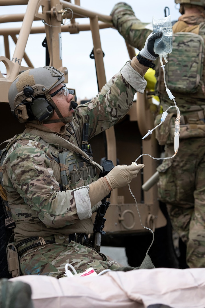 An Alaska Air National Guardsman assigned to the 212th Rescue Squadron, 176th Wing, prepares an intravenous line while responding to a simulated mass-casualty incident during a full mission profile exercise at Joint Base Elmendorf-Richardson, Alaska, Oct. 13, 2021.