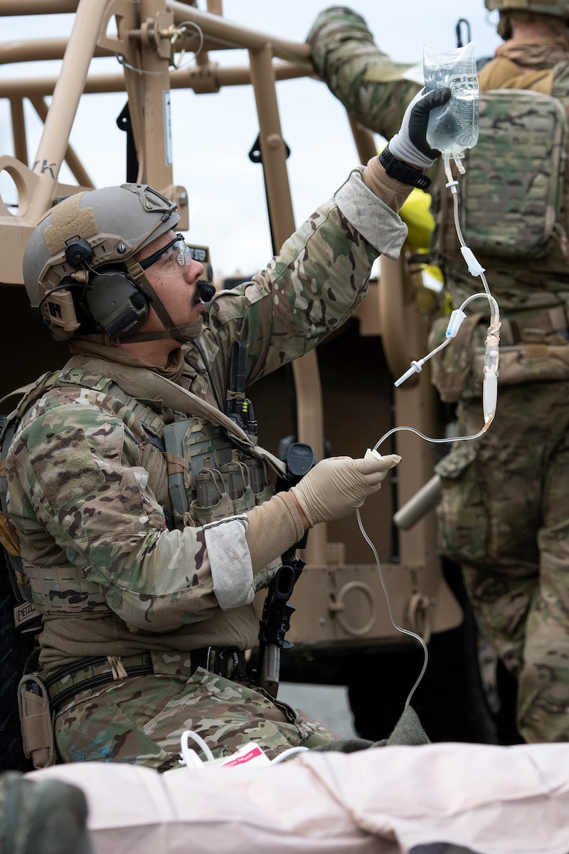An Alaska Air National Guardsman assigned to the 212th Rescue Squadron, 176th Wing, prepares an intravenous line while responding to a simulated mass-casualty incident during a full mission profile exercise at Joint Base Elmendorf-Richardson, Alaska, Oct. 13, 2021.