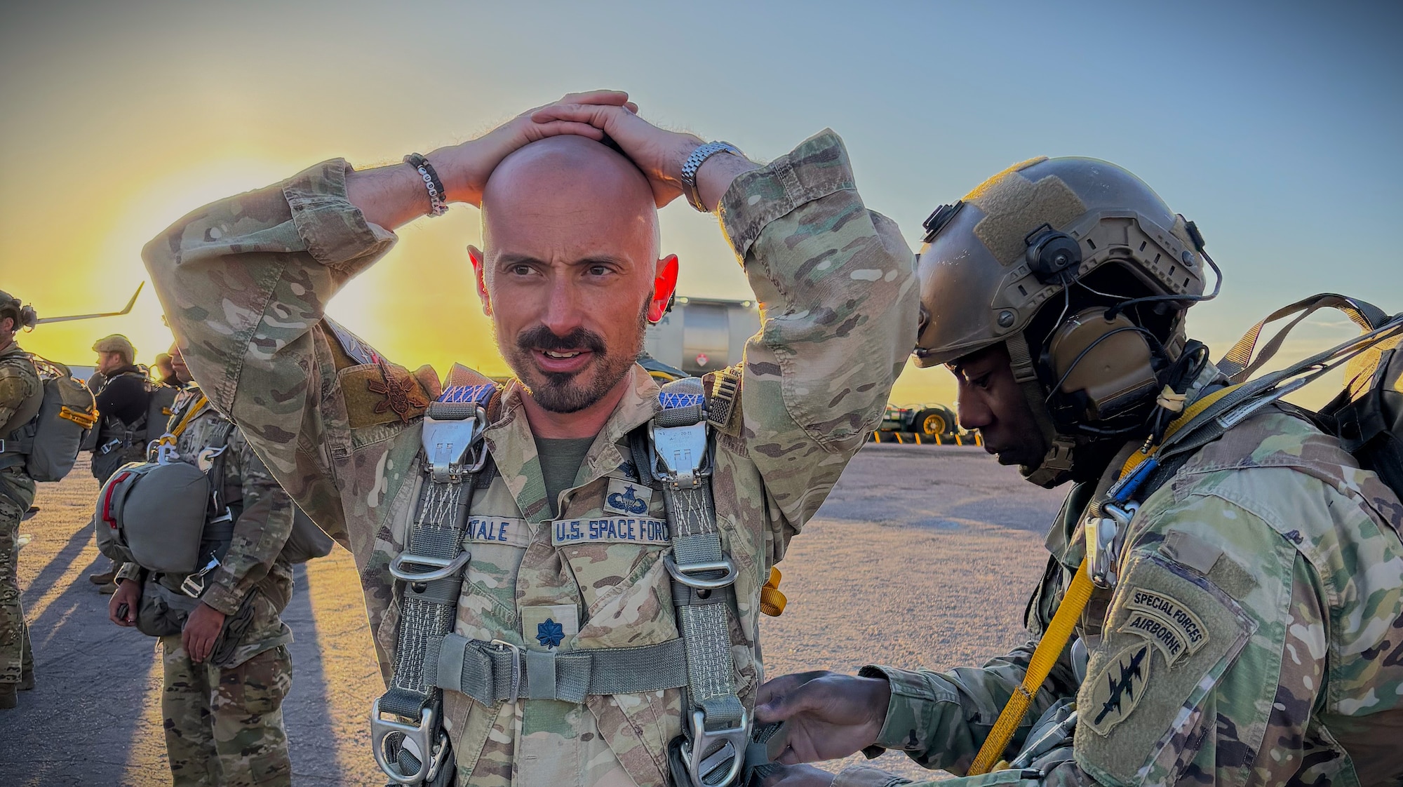 A U.S. Soldier assists a U.S. Guardian in donning his parachute before an airborne operation.