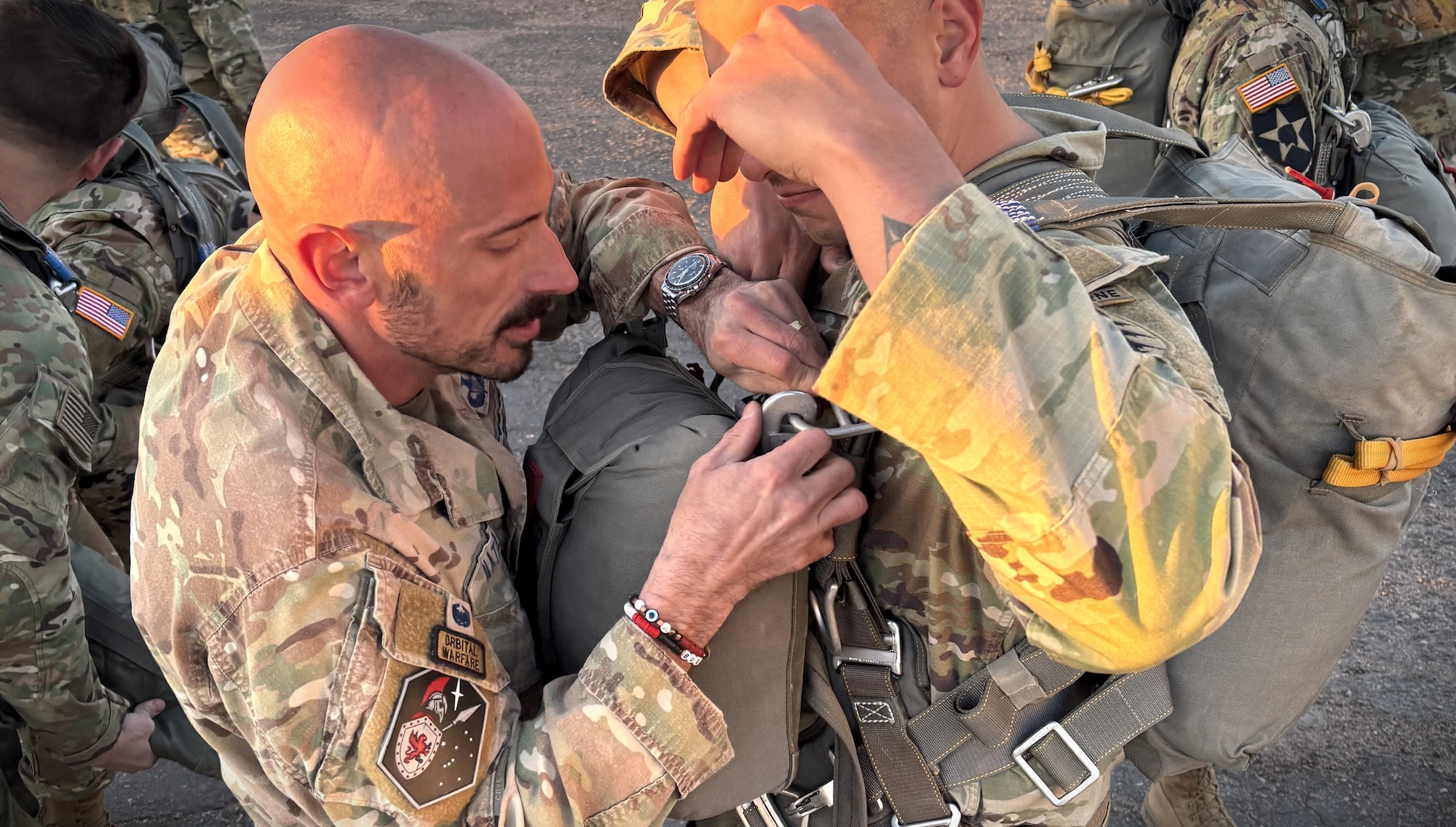 A U.S. Guardian assists a U.S. Solider in donning his reserve parachute before an airborne operation