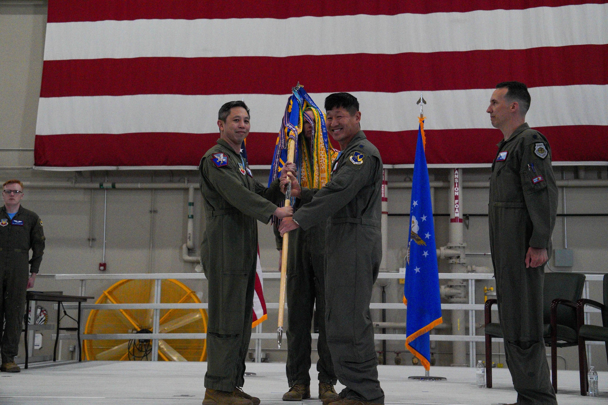 U.S. Air Force Lt. Col. Nathaniel Dull, 11th Attack Squadron outgoing commander, relinquishes command by passing a guidon to Col. Landon Quan, 25th Attack Wing deputy commander of operations, during a change of command ceremony at Creech Air Force Base, Nevada, April 17, 2026.