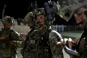 Men stand in military gear.