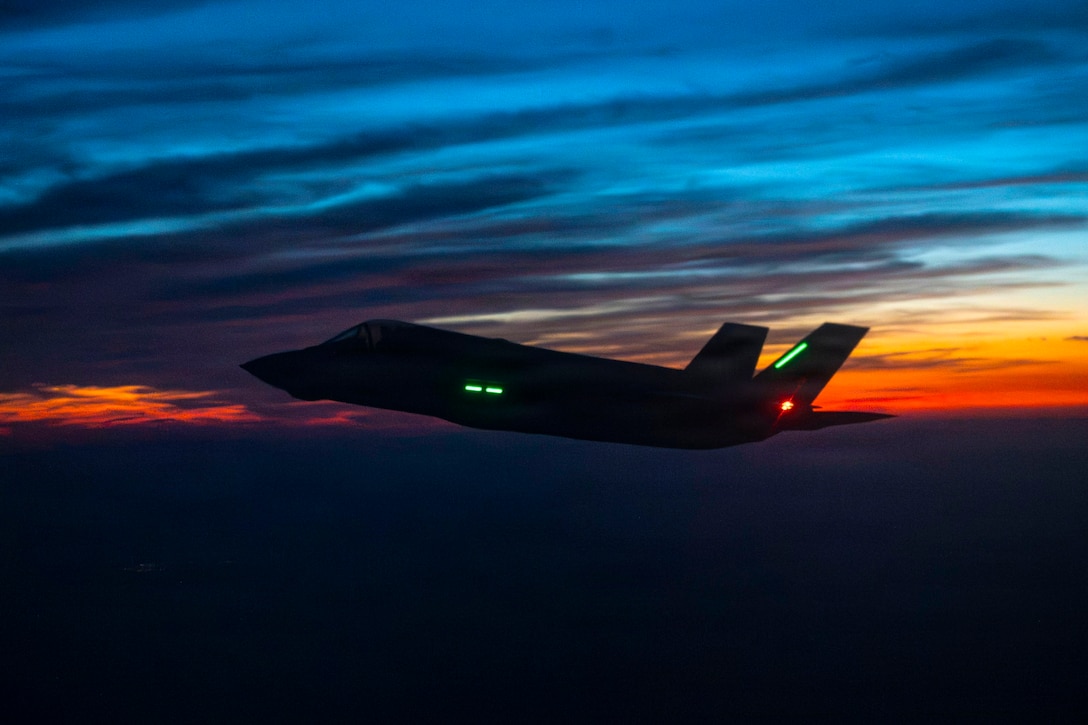 An aircraft flies in a dark blue and orange sky.