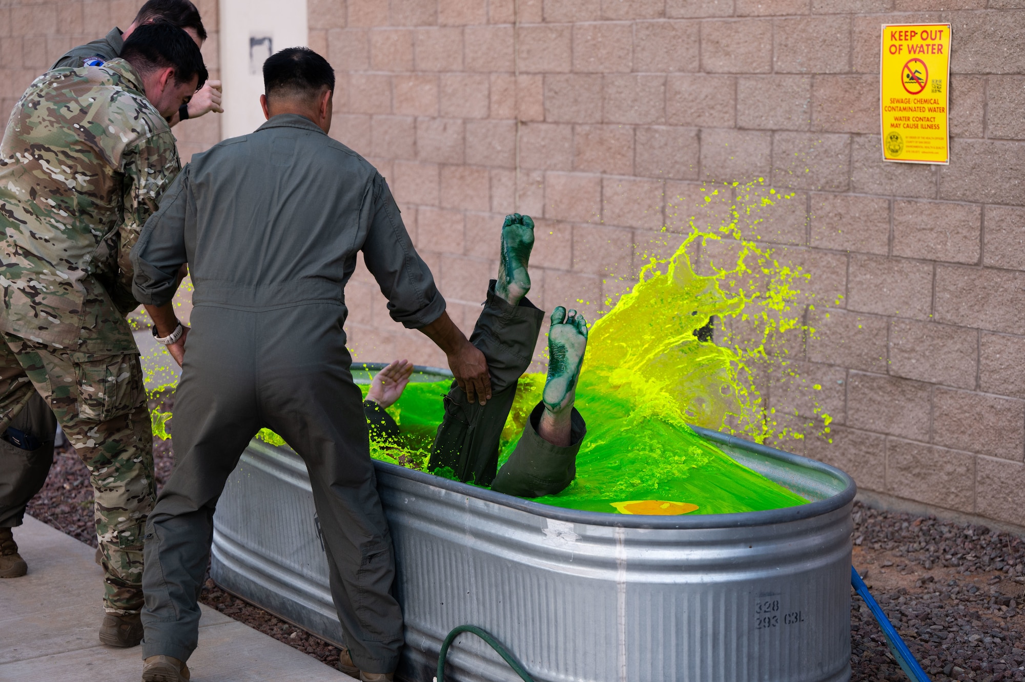 U.S. Air Force Col. Charles Redmond, 355th Wing deputy commander, is dropped into a bath of green water at Davis-Monthan Air Force Base, Arizona, May 12, 2026. The submersion in green water is a tradition among aviators to honor the pilot’s service, covering them in the symbolism and colors that define the rescue community’s identity. (U.S. Air Force photo by Airman Najzee Kuzu)