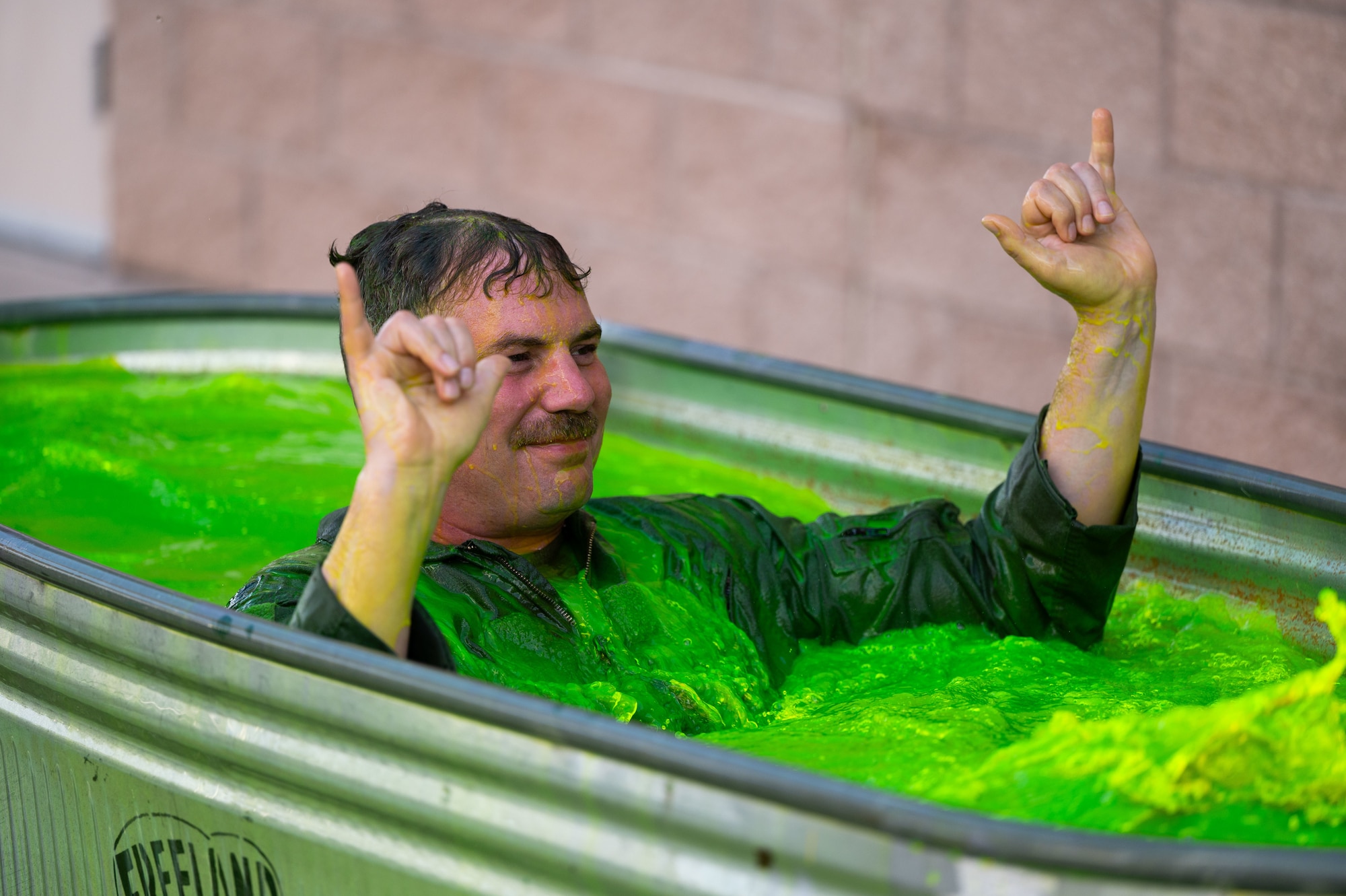 U.S. Air Force Col. Charles Redmond, 355th Wing deputy commander, sits in a bath of green water at Davis-Monthan Air Force Base, Arizona, May 12, 2026. Redmond was dunked in a bath of green water to honor his service as part of a long-standing tradition upon the completion of his “fini” flight, the final of his career at Davis-Monthan. (U.S. Air Force photo by Airman Najzee Kuzu)