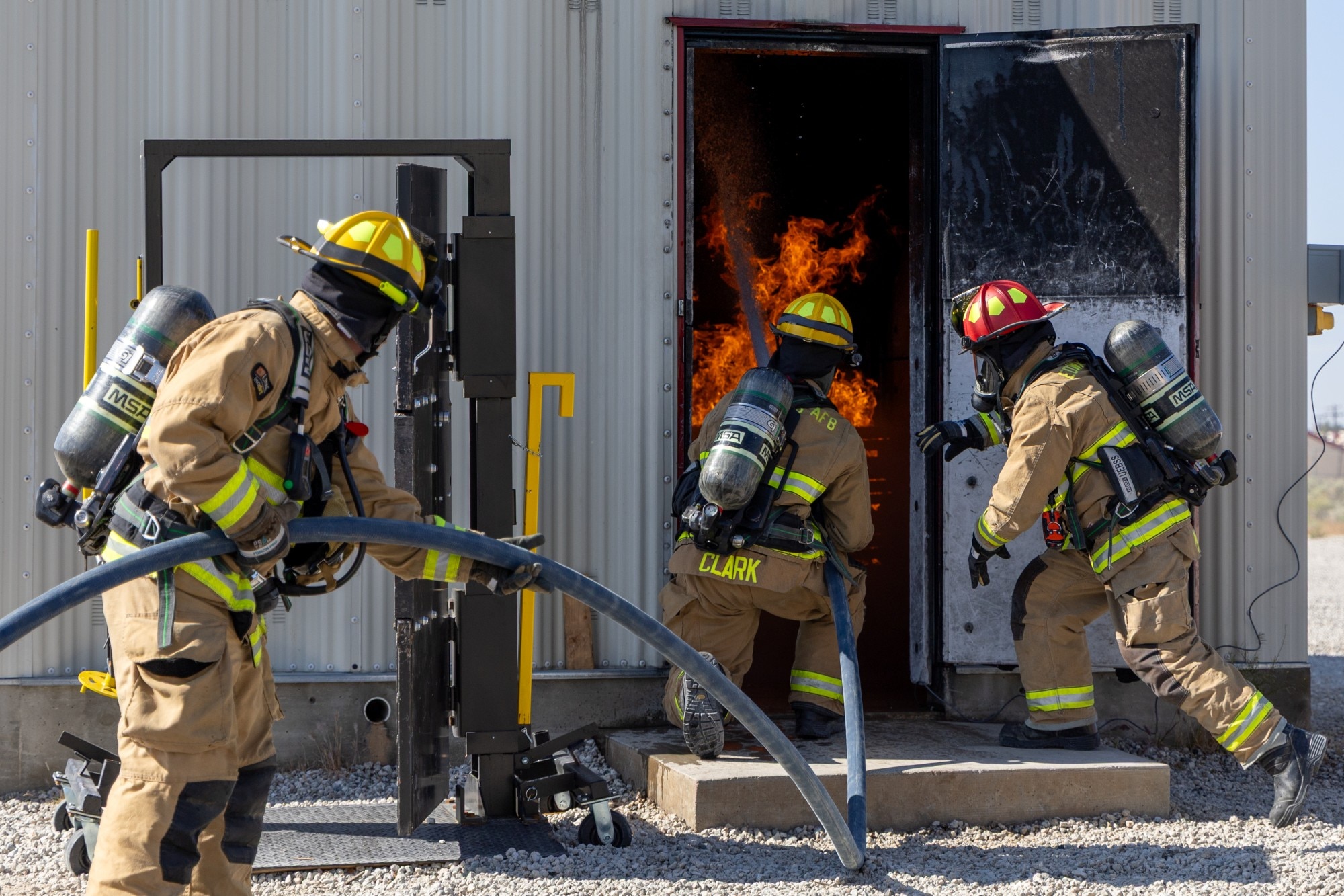 Airman 1st Class Eduardo Mercado, Airman 1st Class Tyler Clark and Capt. Joshua Millan, 812th Civil Engineer Squadron firefighters, direct a charged hose stream onto a simulated structure fire during a training exercise at Edwards Air Force Base, California, May 5. (U.S. Air Force photo by Christian Raterman)