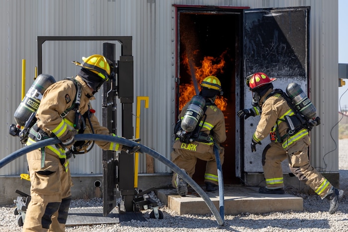 Airman 1st Class Eduardo Mercado, Airman 1st Class Tyler Clark and Capt. Joshua Millan, 812th Civil Engineer Squadron firefighters, direct a charged hose stream onto a simulated structure fire during a training exercise at Edwards Air Force Base, California, May 5. (U.S. Air Force photo by Christian Raterman)