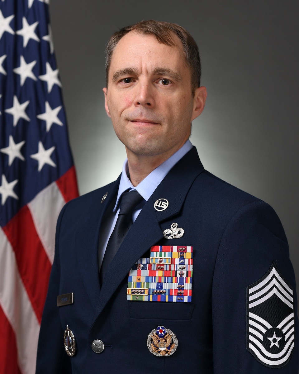 Official Bio of CMSgt. Kevin Ishman with america flag in the background