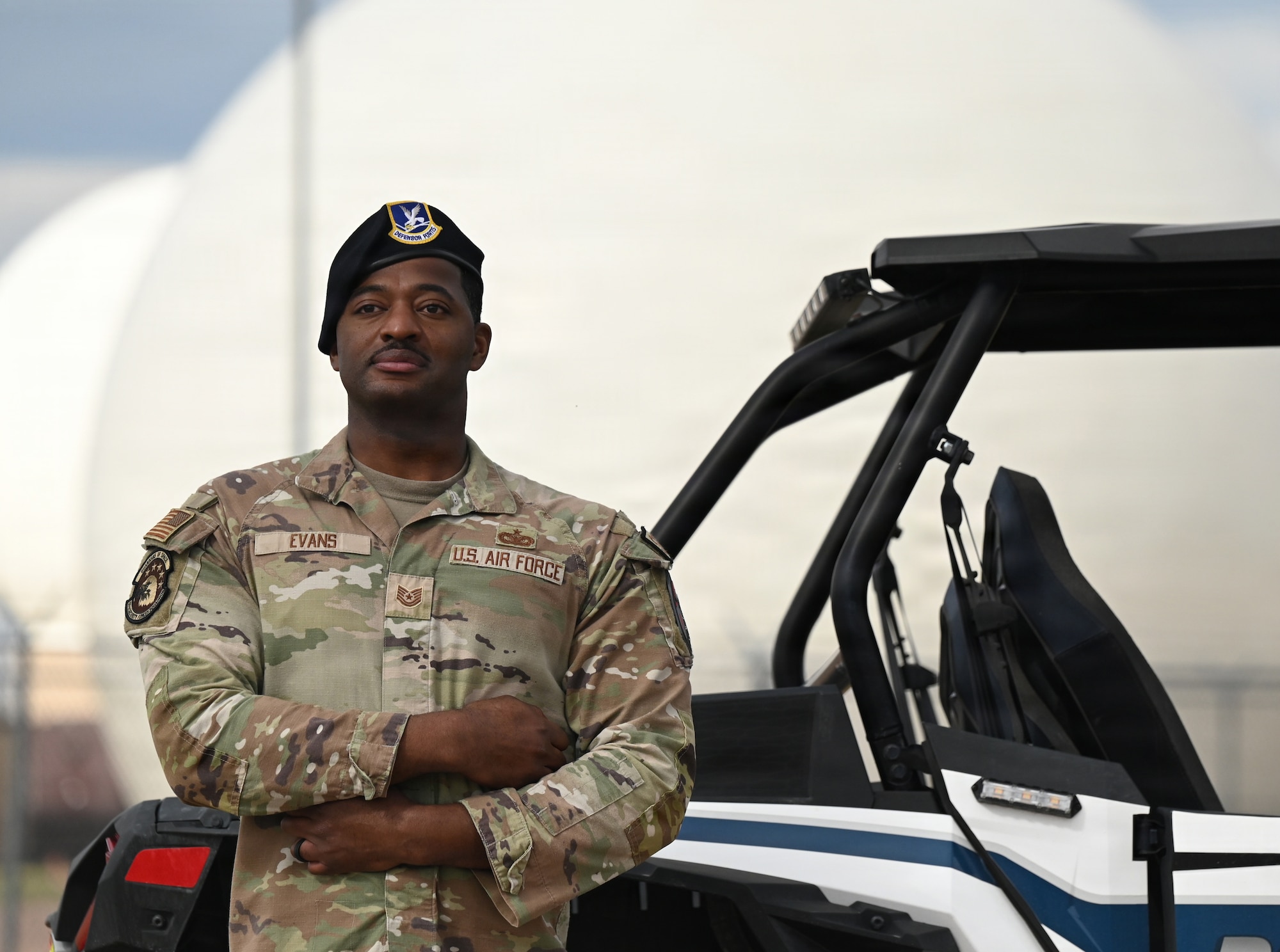A security forces members stands for a photo in front of a radome.