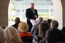 Jim Flook stands and speaks in front of an audience at a ceremony.