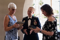 Lt. Col Brittany Lee gives the ID tags to Lorraine Larsen and Suzanne Huberth, both sisters each holding one.