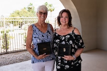 Lorraine Larsen and Suzanne Huberth stand side by side and hold their brother's ID tags posed for a photo.