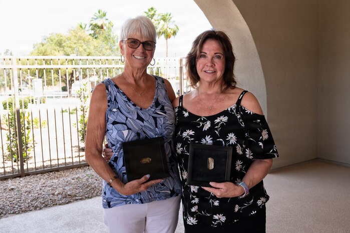 Lorraine Larsen and Suzanne Huberth stand side by side and hold their brother's ID tags posed for a photo.