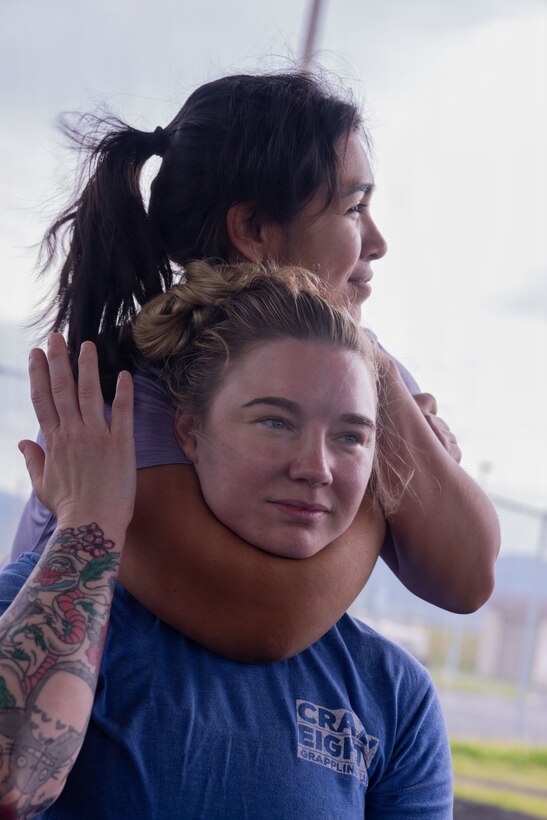 U.S. Marine Corps spouses with Marine Aircraft Group 12, 1st Marine Aircraft Wing, conduct a figure-four variation choke during Spouse Warrior Day at Marine Corps Air Station Iwakuni, Japan, May 8, 2026. The event provided Marine spouses an opportunity to experience elements of military training while strengthening their understanding of the Marine Corps’ mission and daily operations. (U.S. Marine Corps photo by Cpl. Ella Cadby)
