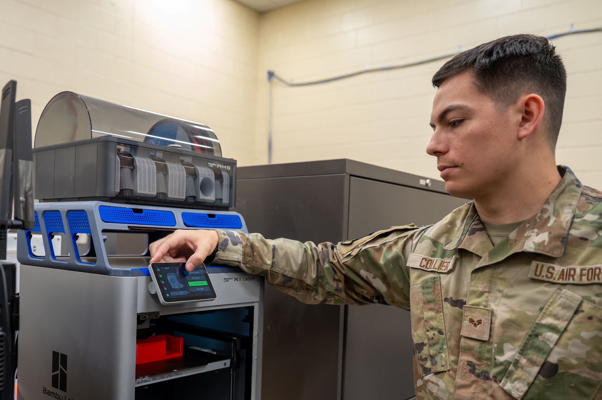 U.S. Air Force Senior Airman Andrew Collier, 325th Maintenance Squadron metals technology journeyman, adjusts the settings of a 3D printer at Tyndall Air Force Base, Florida, April 22, 2026