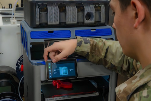 U.S. Air Force Senior Airman Andrew Collier, 325th Maintenance Squadron metals technology journeyman, observes a 3D printer as it produces an aircraft table cover at Tyndall Air Force Base, Florida, April 22, 2026