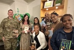 Group of people pose for photo holding books.