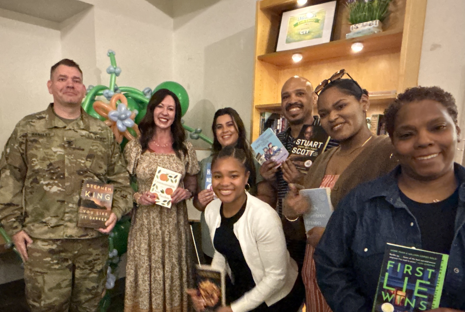 Group of people pose for photo holding books.