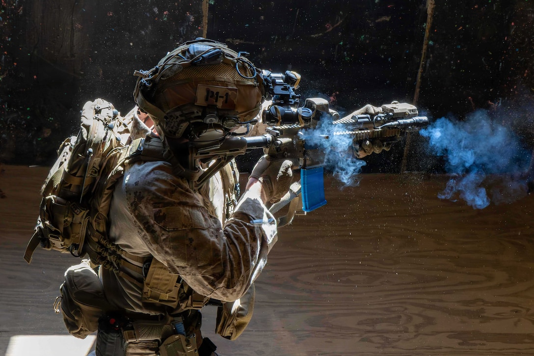 Smoke billows from the weapon of a Marine in protective gear.