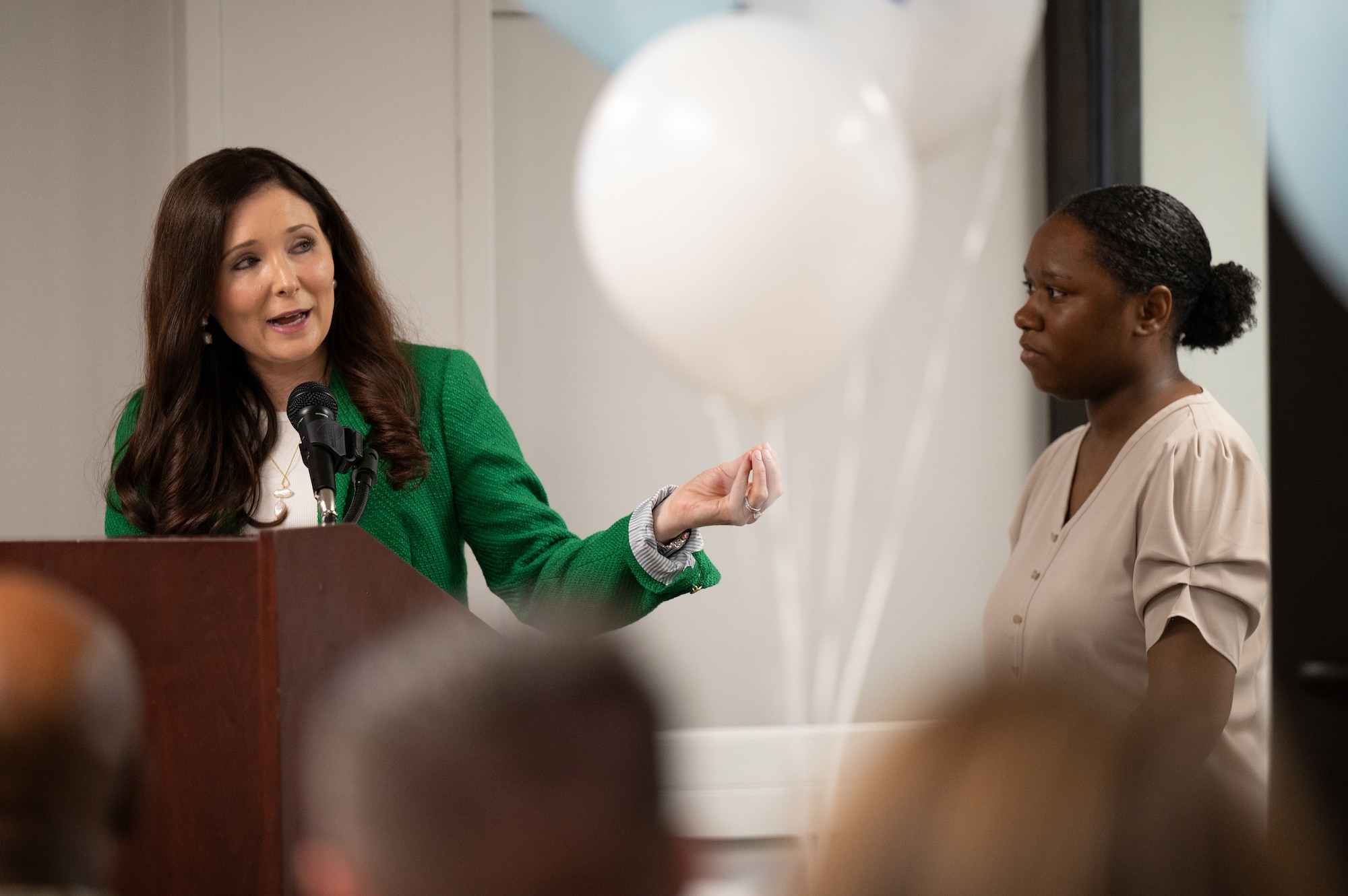 Shannon Eggert, Courtney’s Cove lead coordinator, speaks at a ribbon-cutting ceremony while U.S. Air Force Staff Sgt. Paradise Henson, 305th Air Mobility Wing aviation resource manager and Courtney’s Cove program manager, looks on at Joint Base McGuire-Dix-Lakehurst, N.J., April 2, 2026.