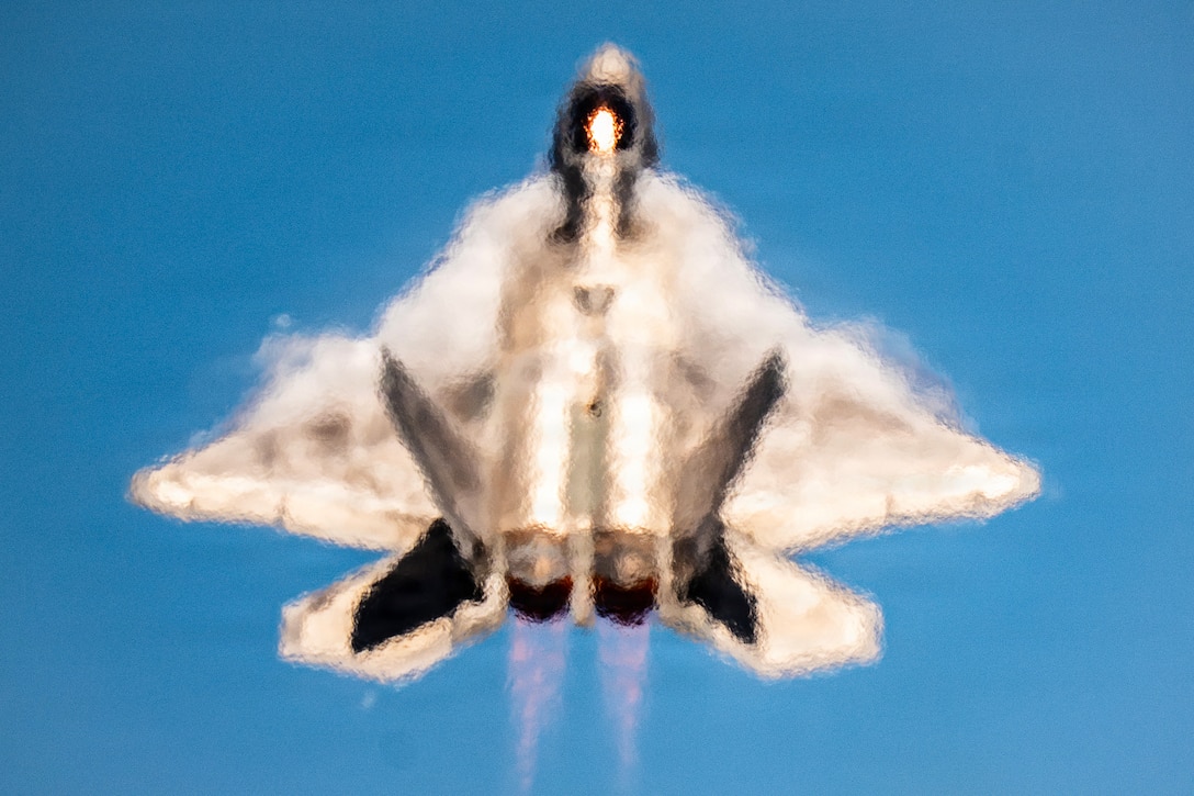 An F-22 raptor flying with its nose straight up appears to have blurred lines.