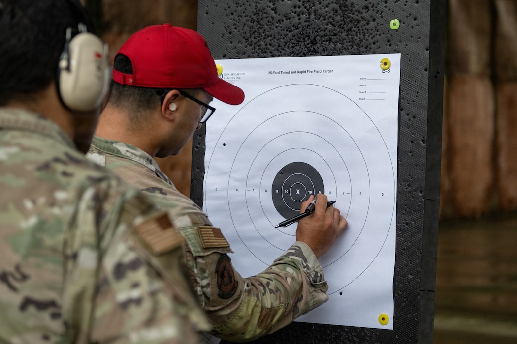 U.S. Air Force Staff Sgt. Victor Chang, 823d Base Defense Squadron combat arms training and maintenance cadre, grades a participant's target during an excellence in competition pistol match at Moody Air Force Base, Georgia, May 13, 2026. The grading process ensured accurate scoring while reinforcing safe weapons handling and qualification standards. (U.S. Air Force photo by Airman 1st Class Noah Noonan)
