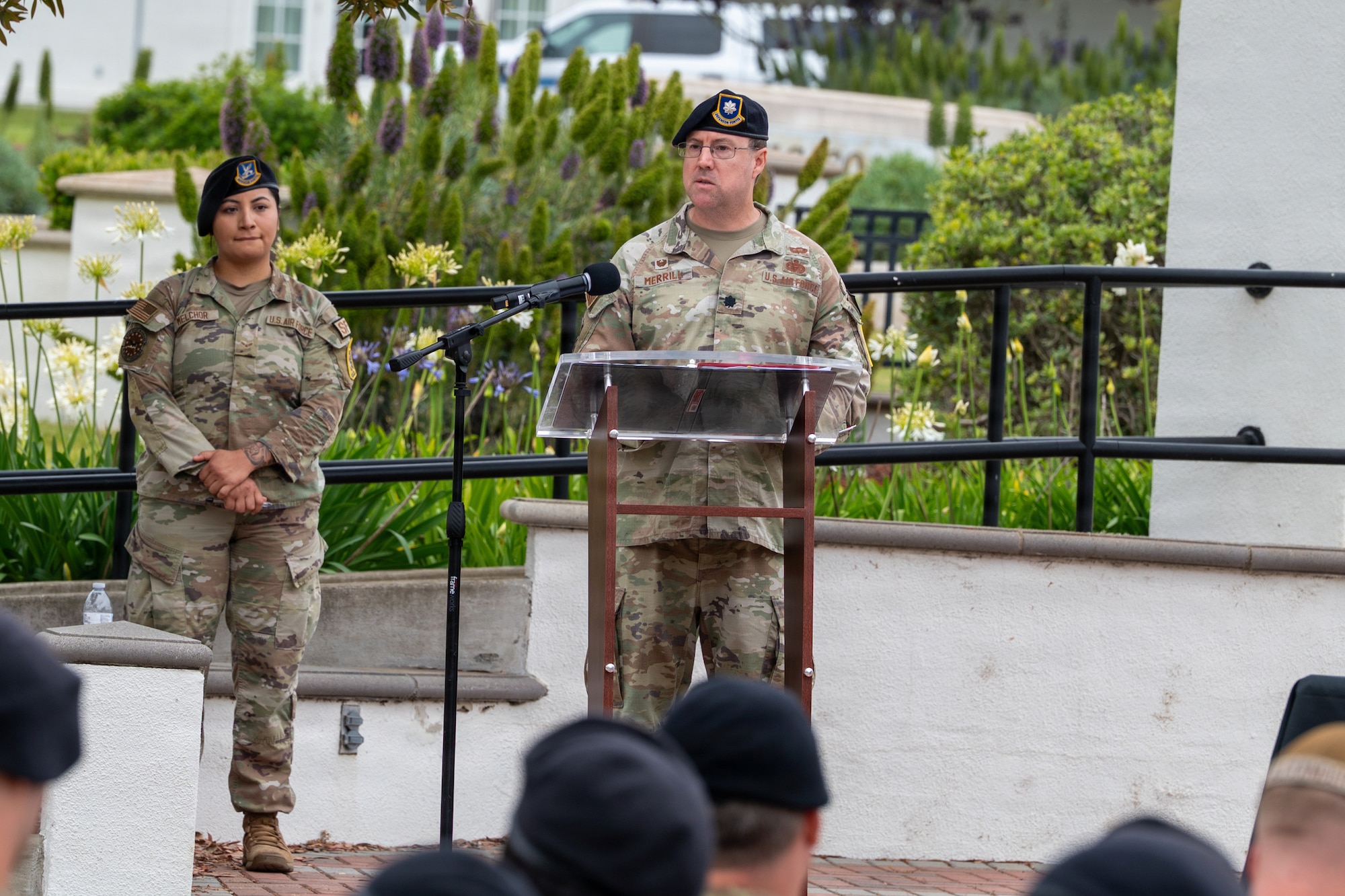 U.S. Air Force Lt. Col. Joseph Merrill speaks behind a podium to a crowd of people outside.