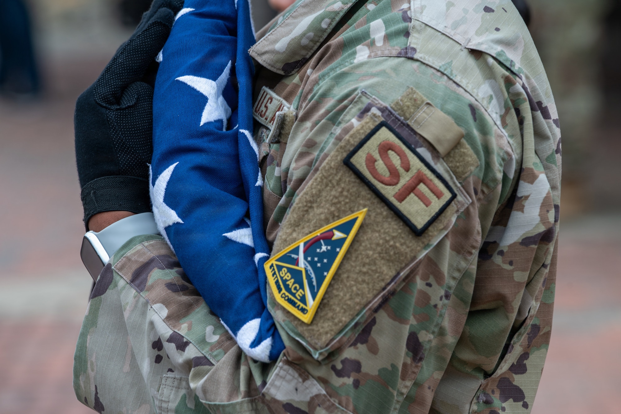 A person holds a triangle-folded American flag at their chest