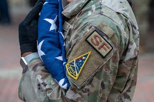 A person holds a triangle-folded American flag at their chest