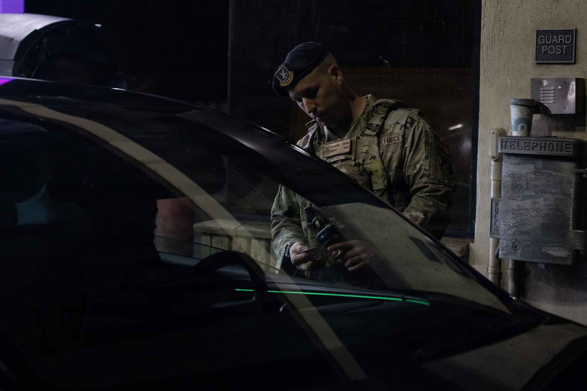 U.S. Air Force Airman checks an I.D. during the night at a security checkpoint.