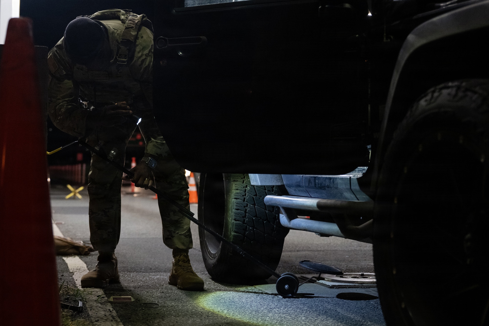 U.S. Air Force Airman uses a mirror to check under a vehicle.