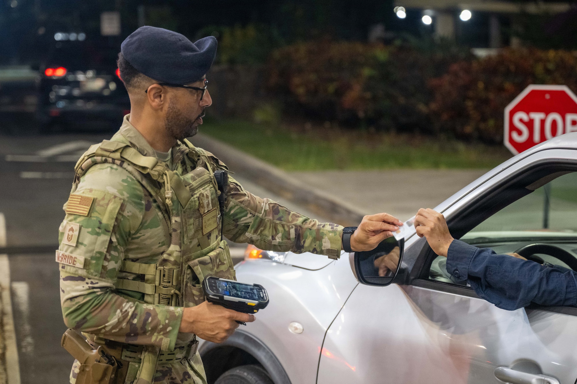 U.S. Air Force Airman grabs an Identification card to with base access from a driver.