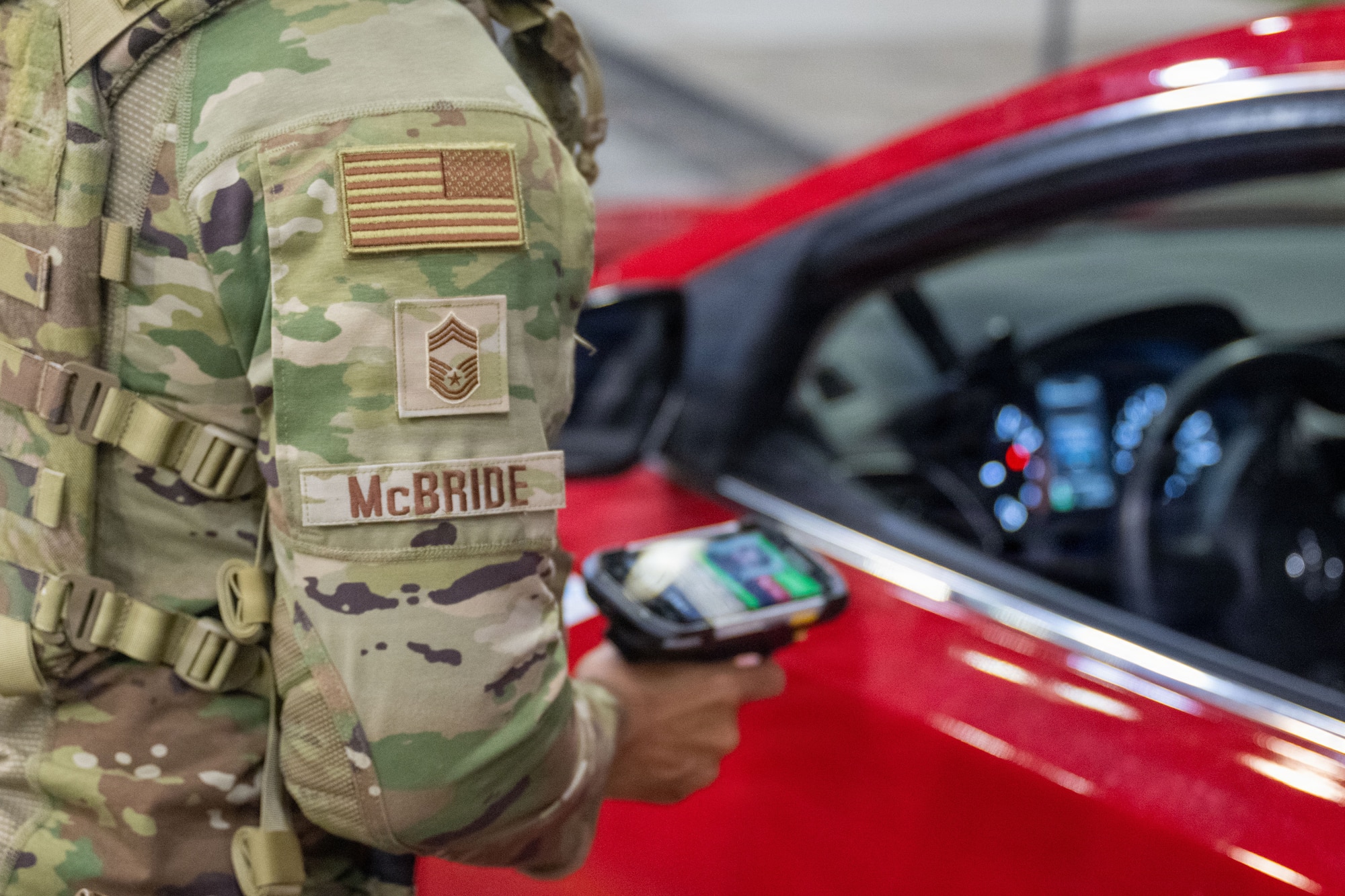 A photo from behind an airman's shoulder as he scans an Identification Card with military base access.