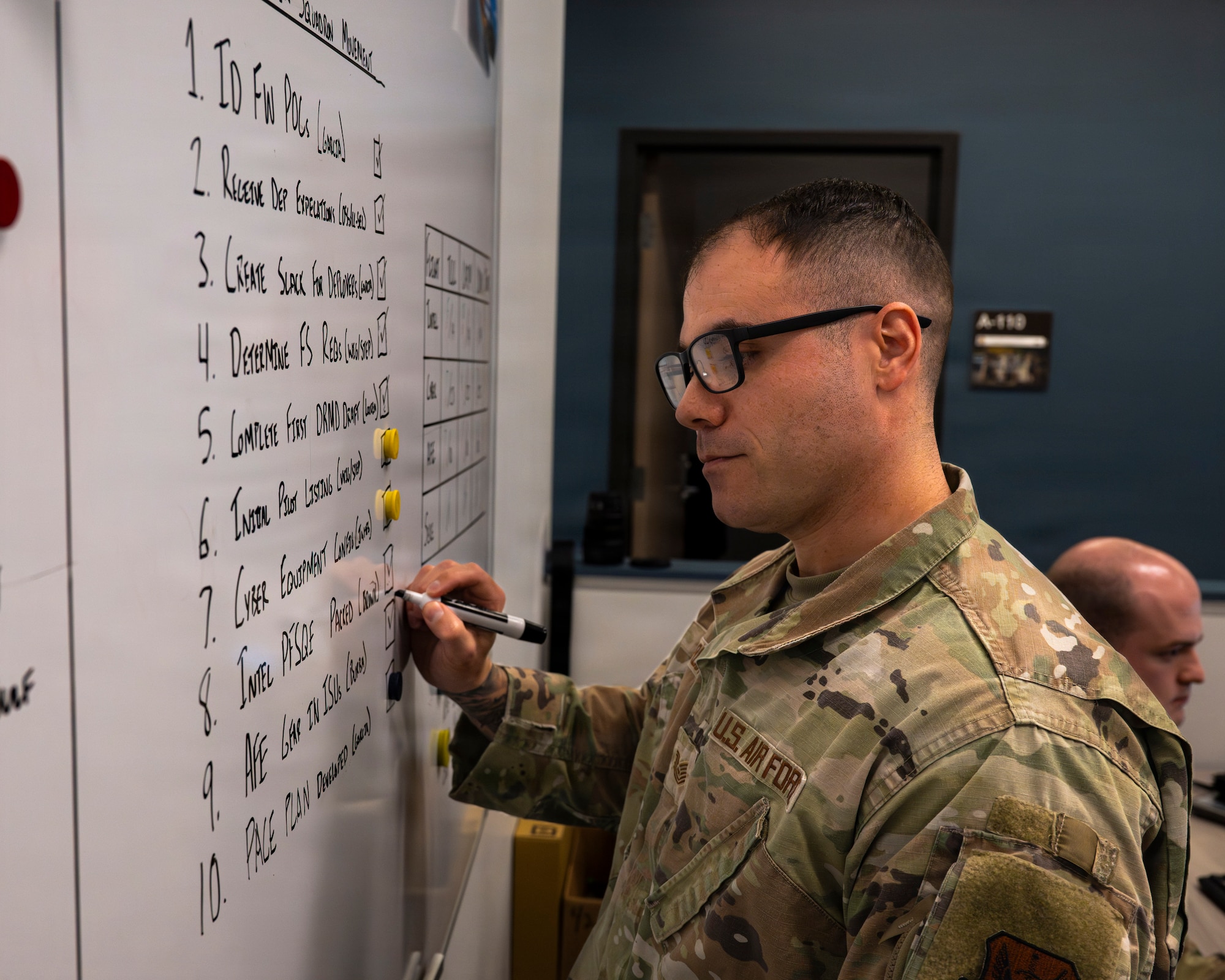 A photo of an Airman making a list on a whiteboard