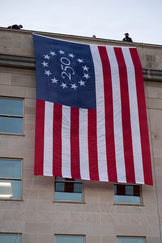 A large American flag hangs off the side of a large, five-story building.