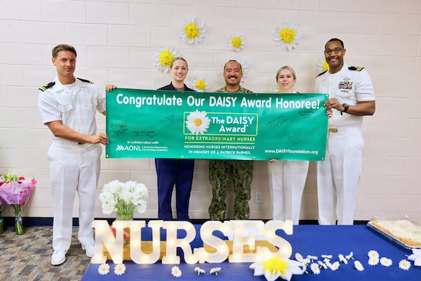 From left to right, Lt. j.g. Rory Sherban, Lt. Isabel M. Jackabon, Lt. j.g. Duane Aldous V. Daquioag, Lt. Corinne Hassett and Lt. Ricardo Porter pose for a photo with a DAISY Award banner during a recognition ceremony at Naval Hospital Twentynine Palms May 12, 2026. The ceremony recognized nurses for their compassion, professionalism and commitment to patient-centered care across the command. (U.S. Navy photo by Christopher Jones, NMRTC / NH Twentynine Palms public affairs officer)