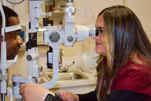 Catherine Ortiz (right), a Doctor of Optometry student from Western University of Health Sciences, conducts an eye examination with Hospital Corpsman 2nd Class Emilio Matthew at Naval Hospital Twentynine Palms in April 2026. Ortiz completed a clinical rotation at the hospital as part of a partnership that provides optometry students with hands-on experience in a military healthcare environment. (U.S. Navy photo by Hospital Apprentice Evelyn Zermeno)