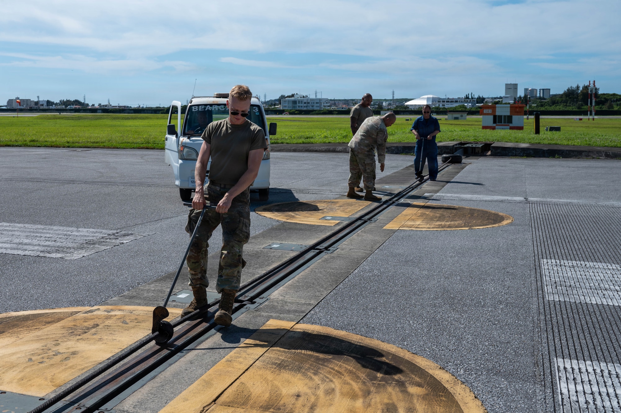 Service members adjusting gears on machinery.