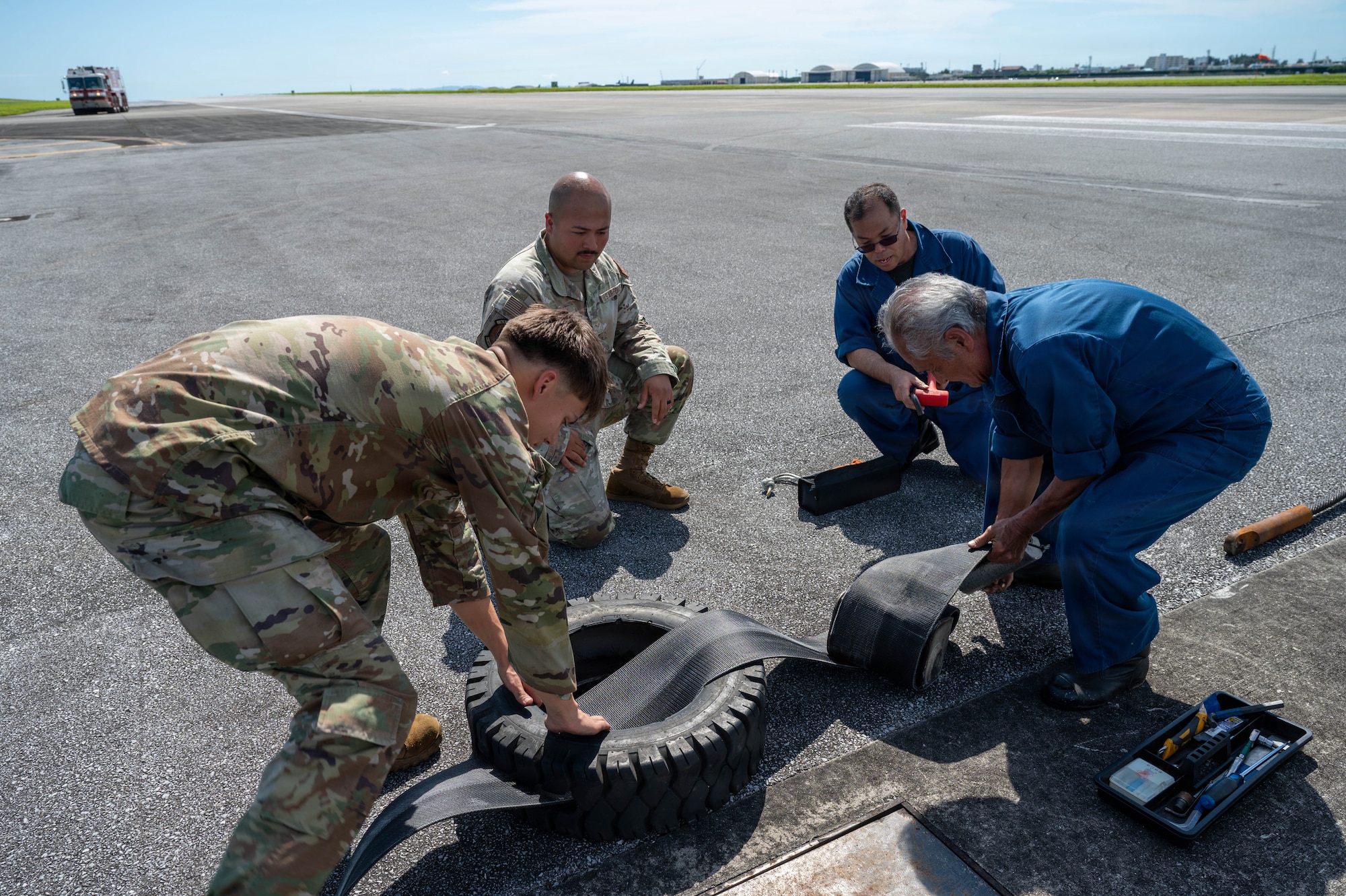 Service members and contractors work on machinery.