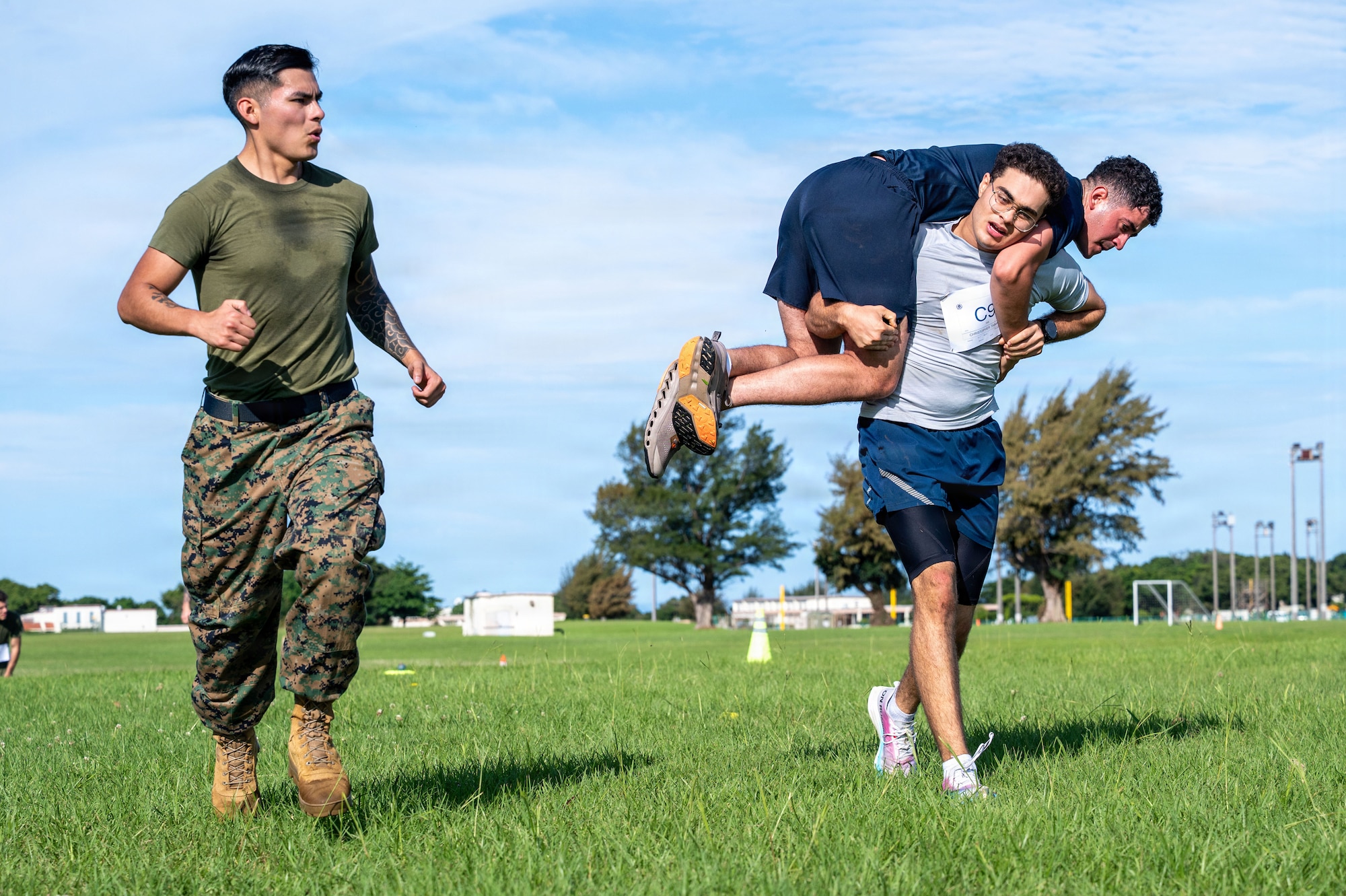 U.S. Air Force Airman Christopher Tabarani, 18th Civil Engineer Squadron electrical systems apprentice, carries a simulated fallen teammate while maneuvering under fire during the Warrior Gauntlet at Kadena Air Base, Japan, May 8, 2026. Participants moved through the course in mixed-branch groups, building familiarity between units that share training, missions and daily operations across Okinawa. (U.S. Air Force photo by Senior Airman Greydon Furstenau)