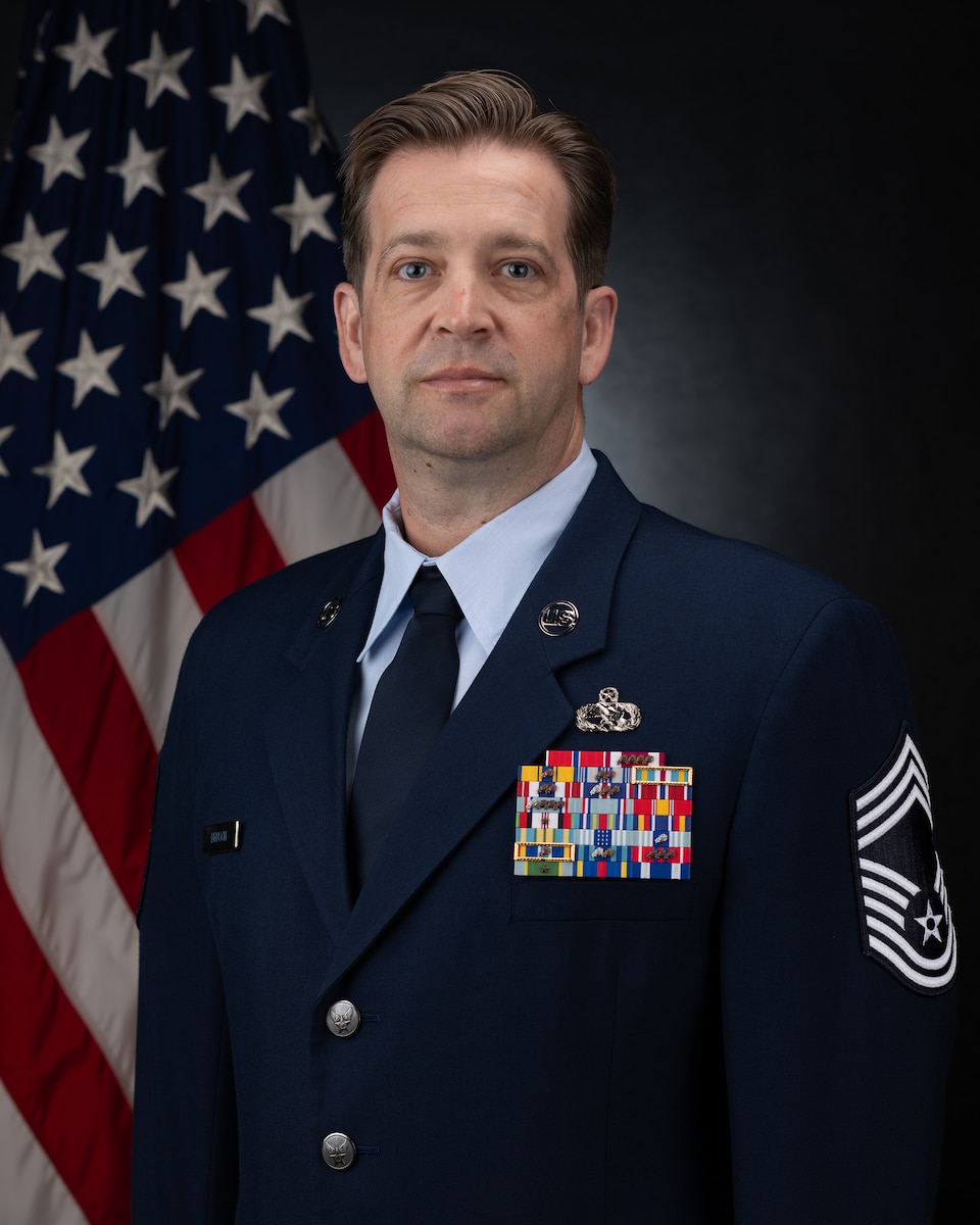 A uniformed member in front of the US Flag