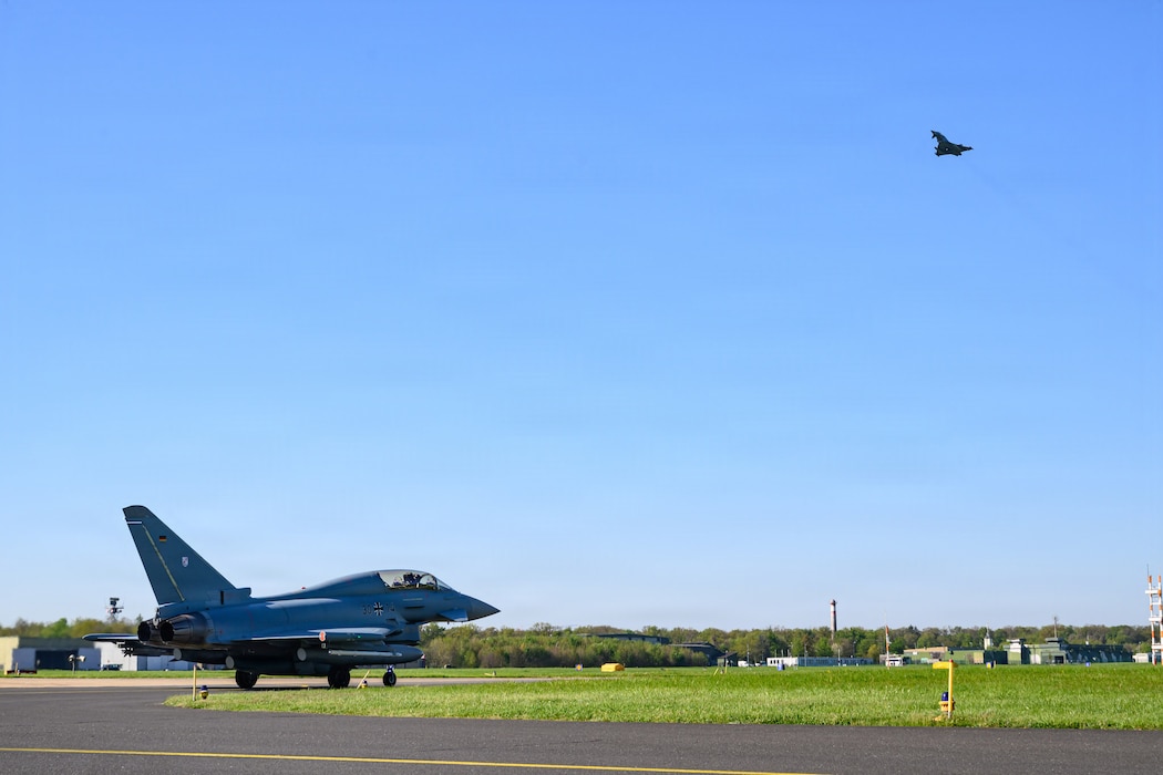 An aircraft takes off while another aircraft taxis below it.