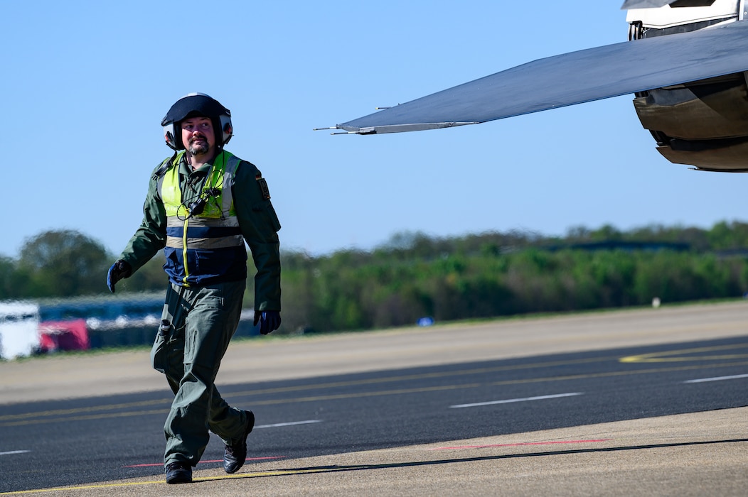 A person walks around the tail of an aircraft.
