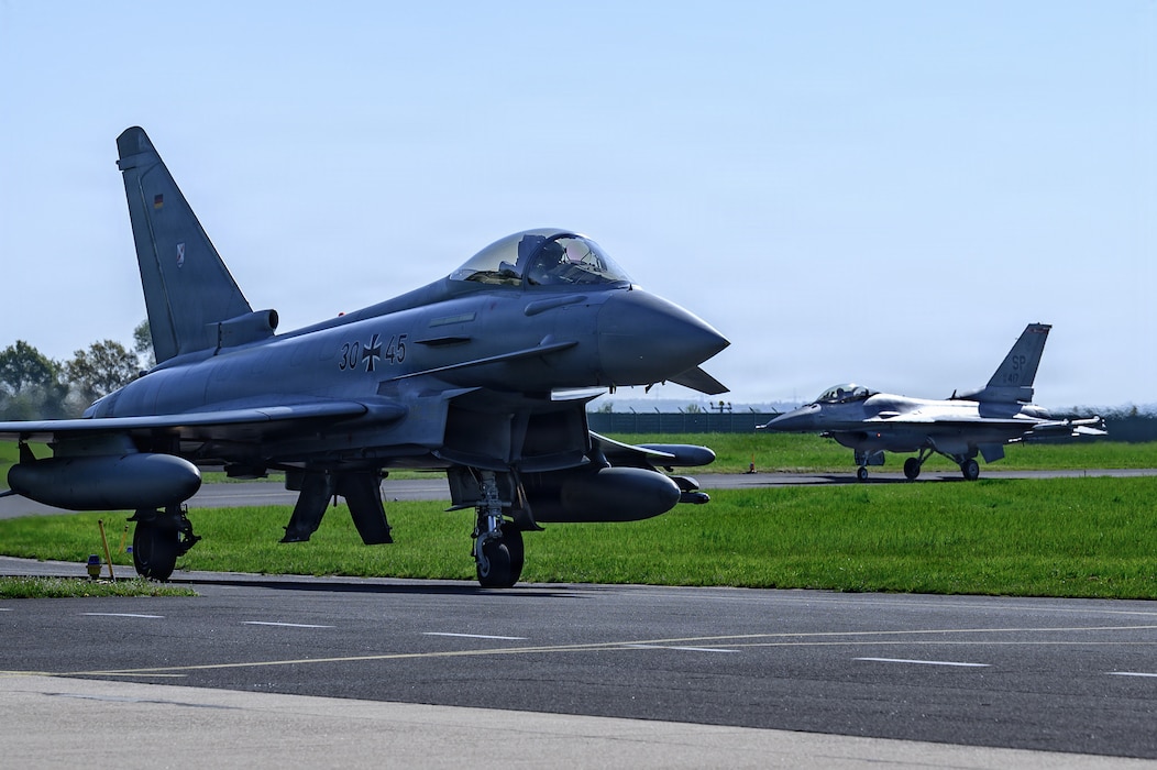 A pair of aircraft taxi on a flightline.