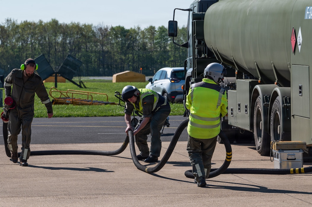 A group of people return a fuel hose to the fuel truck.