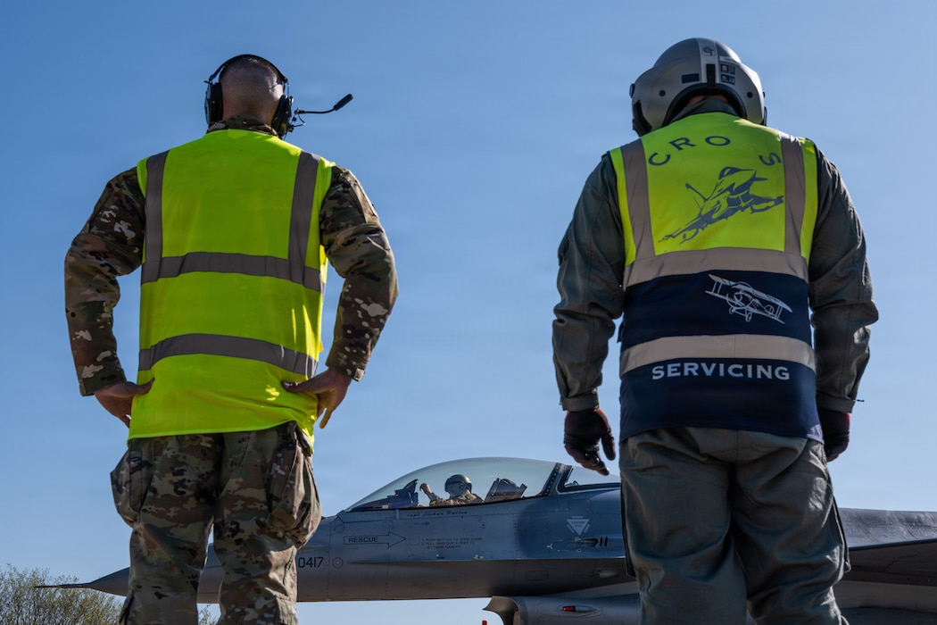Two people stand and observe an aircraft.