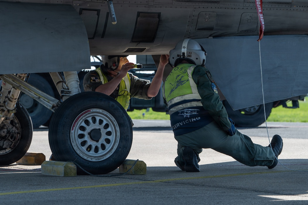 A person crouches under an aircraft.