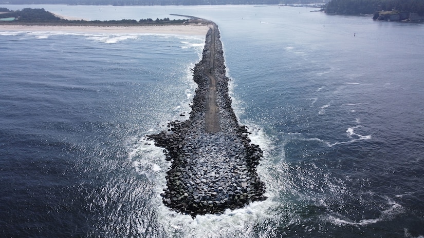 Image of a jetty protruding out from the coast line into the ocean.