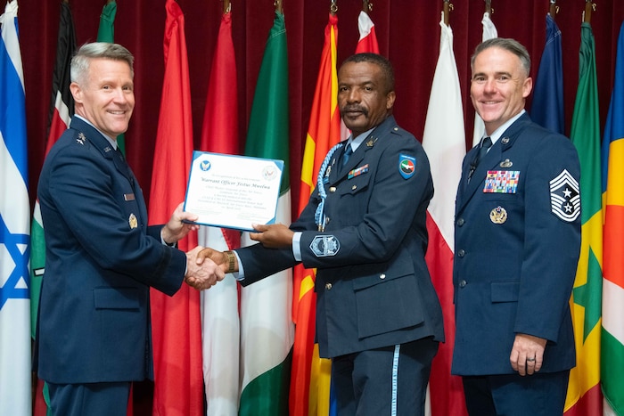 U. S. Air Force Lt. Gen. Daniel H. Tulley, Air University commander and president, and Chief Master Sergeant Raun M. Howell, AU command chief, induct Zambian Air Force Chief Master Sergeant of the Air Force Warrant Officer Festus Mwelwa into the 2026 International Honor Roll at Maxwell Air Force Base, Alabama, Apr. 10, 2026.