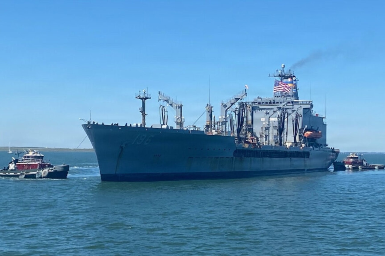 Two tugboats in a body of water guide a large ship into port.